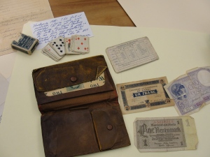 The contents of George Adams, Sr.'s wallet that he carried in France, 1917, which includes French currency, Army registration card, and a deck of cards that George passed down to his son. 
